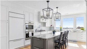 A modern kitchen with white cabinetry, a large island, and pendant lighting.