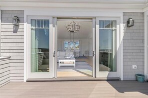 Enter a stylish living space with a sliding glass door, contemporary chandelier, and comfortable sofa.