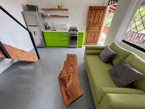 A compact living space with a kitchenette, a green sofa, and a wooden coffee table.