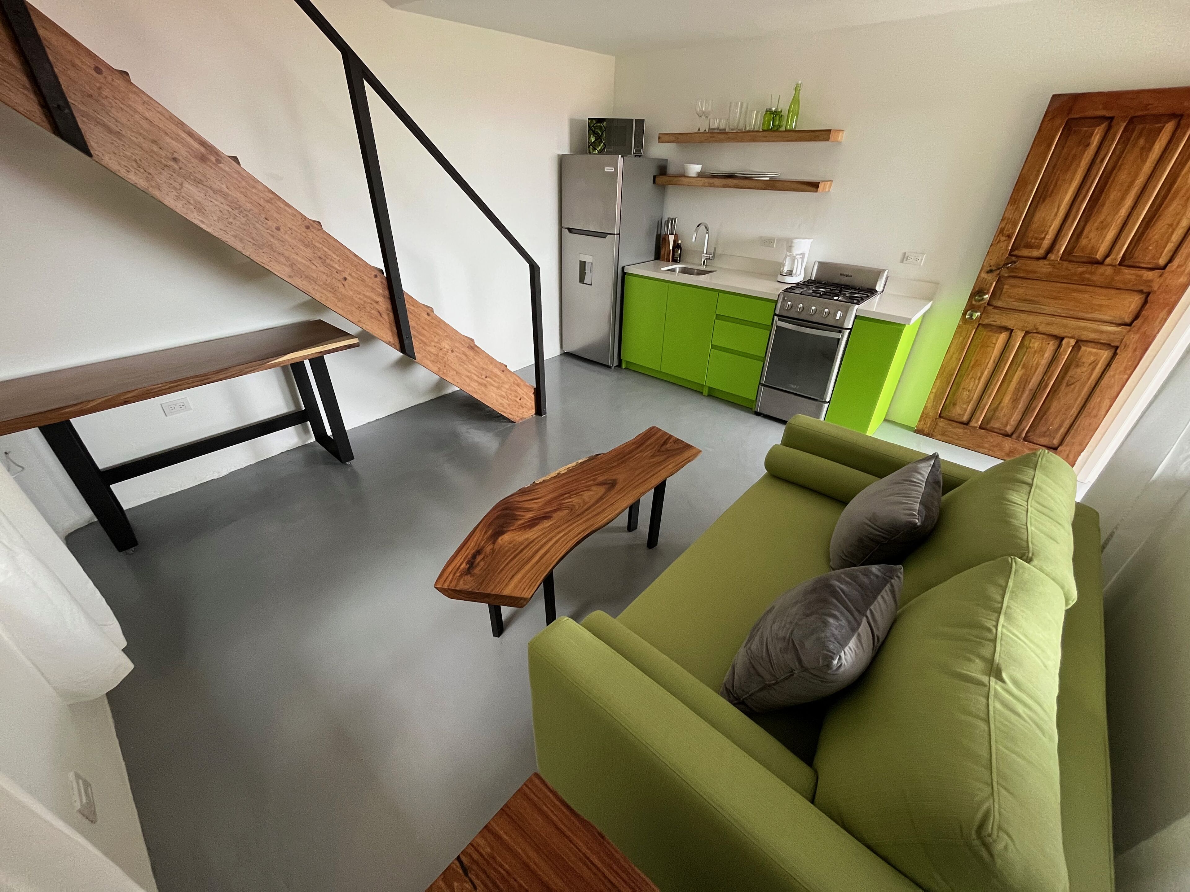 A modern kitchen with green cabinets, a built-in oven, and a coffee maker.