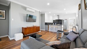 Ein modernes Wohnzimmer mit einem grauen Sofa, einem Holzschrank und einem Flachbildfernseher.