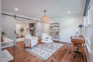 A modern living room with a fireplace, white sofas, a coffee table, and a dining area with a wooden table and chairs. - Spacious, Modern 5B in Mason by I-71, Kings Island (Mason)