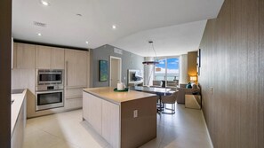 A modern kitchen with built-in appliances, a central island, and a dining area with a view.