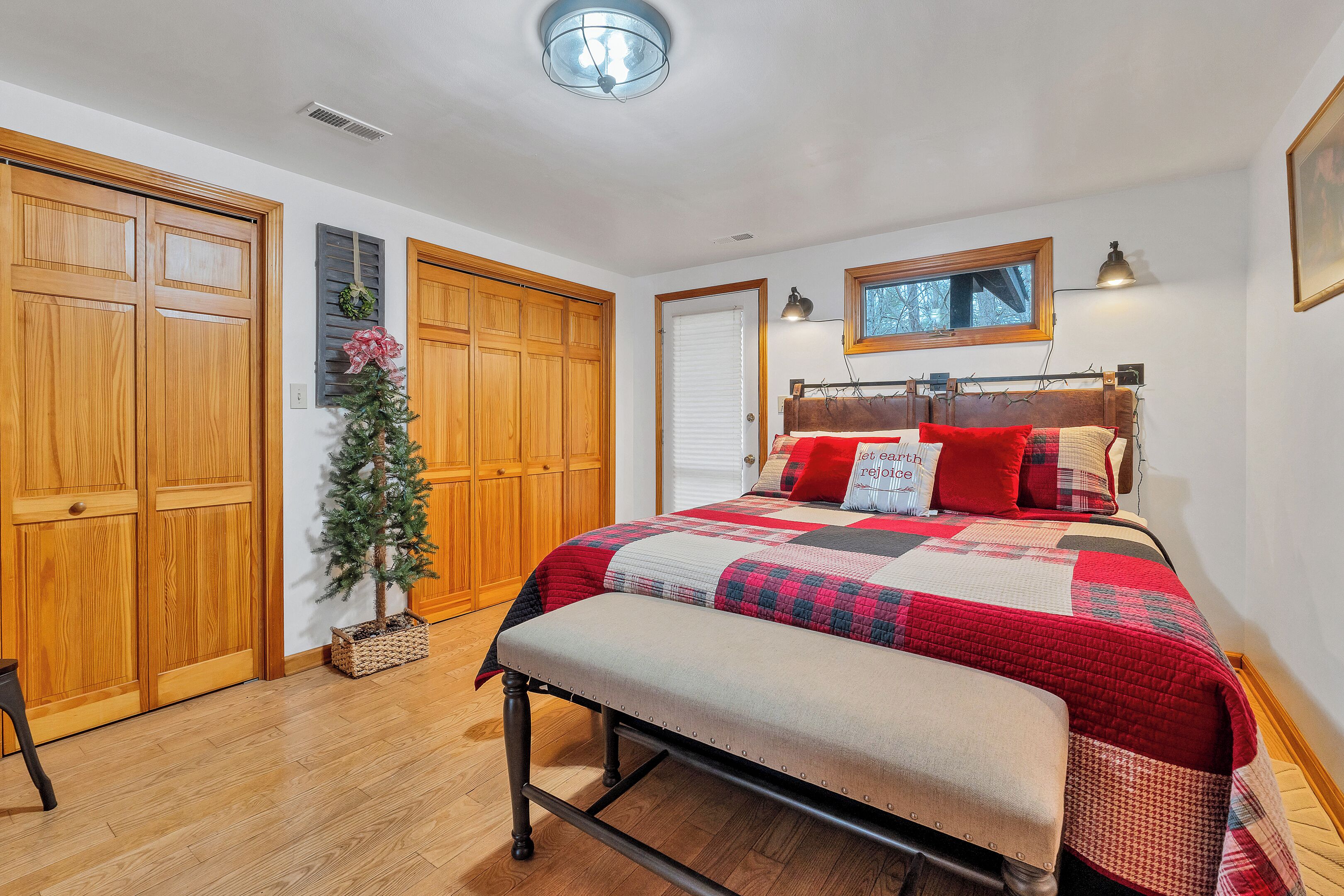 A bedroom with a large bed, wooden wardrobe, and a small Christmas tree.