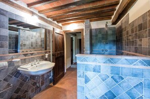 Een badkamer met een wastafel, spiegel, douche en betegelde wanden.
