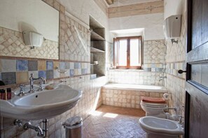 Een badkamer met een groot wastafel, een toilet, een bad en een bidet.
