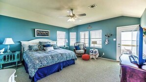 A bedroom with a bed, a chair, a small table, a lamp, and a ceiling fan.