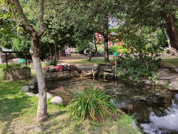 A serene garden with a small stream, stone benches, and lush greenery.