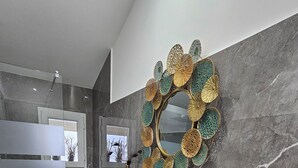 A modern bathroom with a white sink, a gold vase, and a decorative mirror with a floral pattern. - La Punta (San Giovanni la Punta)