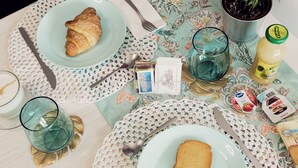 A breakfast table with croissants, toast, a glass of juice, and a bottle of juice. - La Punta (San Giovanni la Punta)