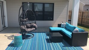 A patio with a hanging chair, a sofa, and a patterned rug. - Beautiful New House in great Northern neighborhood- close to all!  (Fort Wayne)