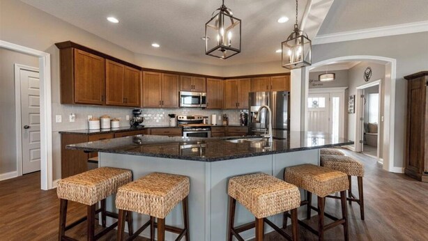 A spacious kitchen with wooden cabinets, a large island with bar stools, stainless steel appliances, and pendant lighting. - Beautiful New House in great Northern neighborhood- close to all!  (Fort Wayne)