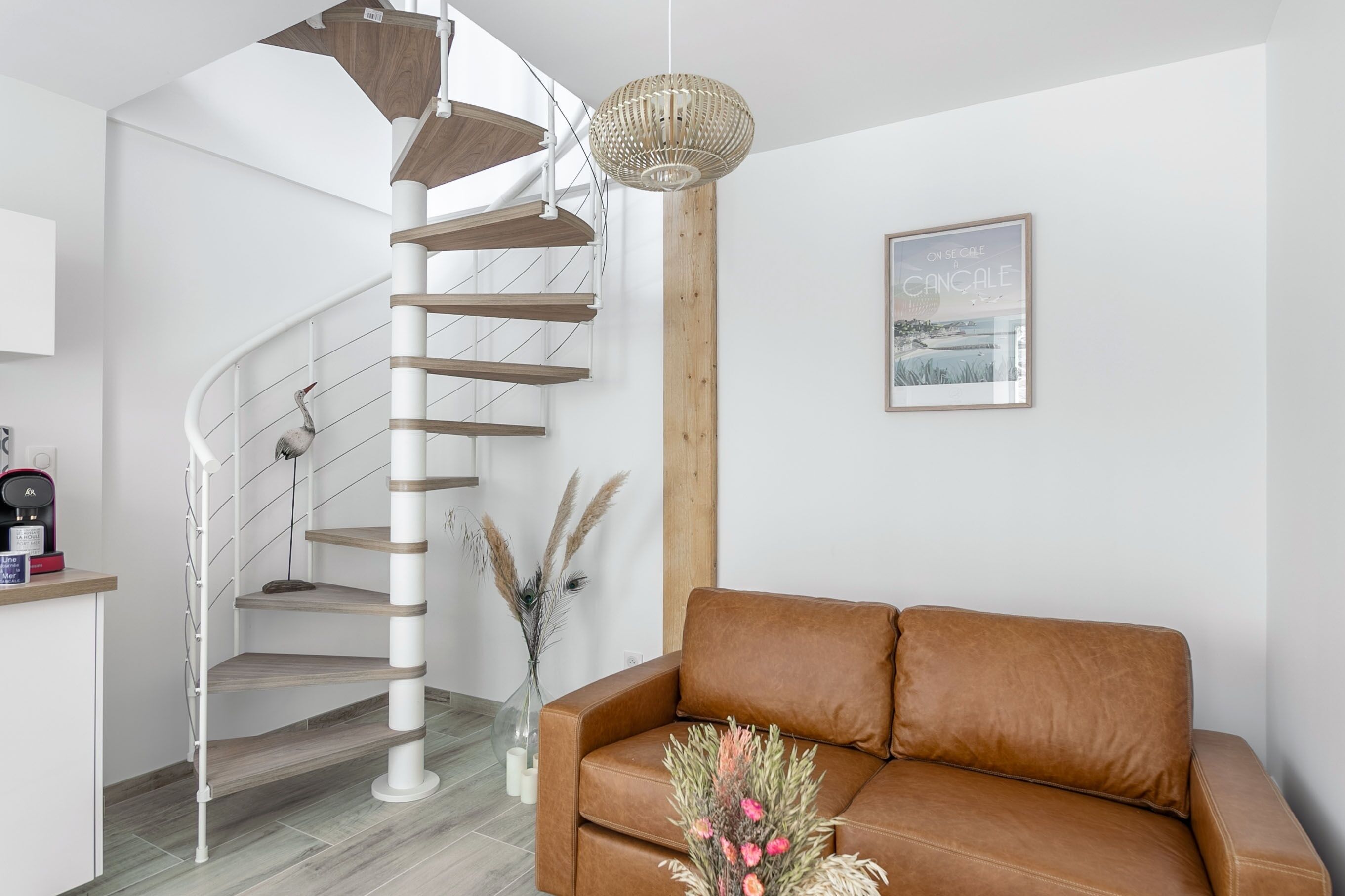 A modern interior with a spiral staircase, a brown leather sofa, and a wooden accent wall.