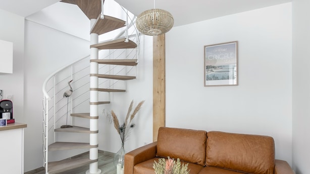 A modern interior with a spiral staircase, a brown leather sofa, and a wooden accent wall. - Le Coco de Cancale - Duplex proche mer (Cancale)