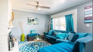 A living room with a blue sofa, a patterned rug, and a ceiling fan.