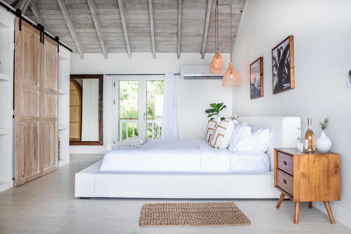 A spacious bedroom with a large bed, wooden wardrobe, and a view of greenery outside.