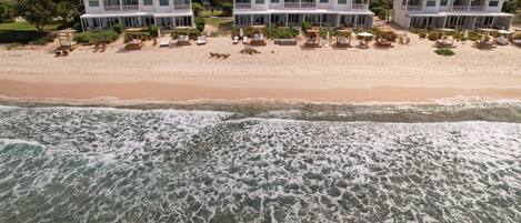 Una propiedad frente a la playa con varias casas blancas, una playa arenosa y olas del océano.