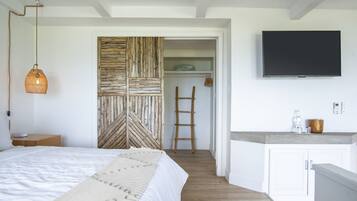 Ein Schlafzimmer mit einem Bett, einer Hängeleuchte, einer Holzvertäfelung, einer Leiter, einem Fernseher und einer Küchenzeile.