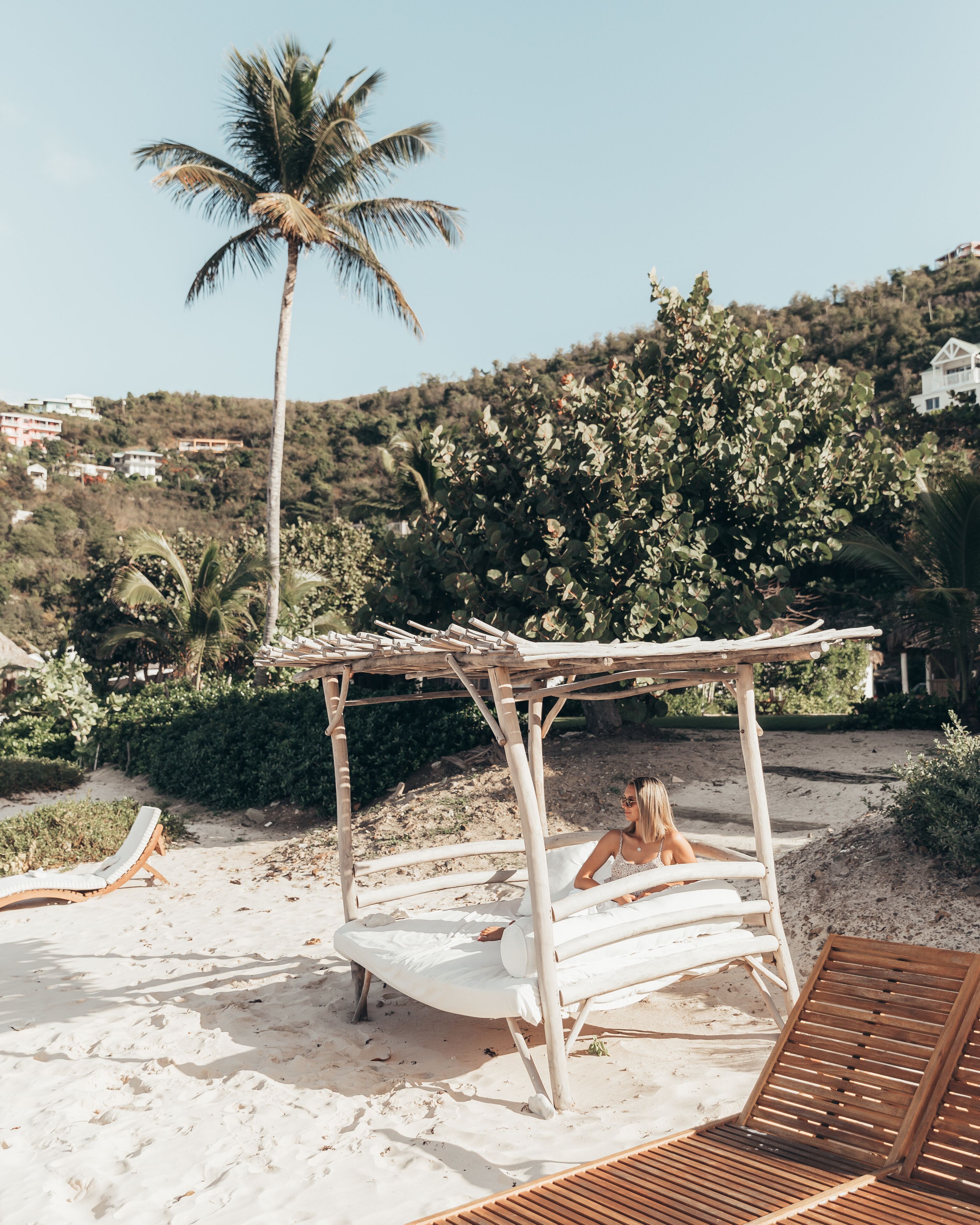 Una playa con una pérgola de madera y sillones de descanso.
