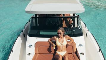 A boat with a Garmin device on the bow, a woman in a bikini on the deck, and clear turquoise water.