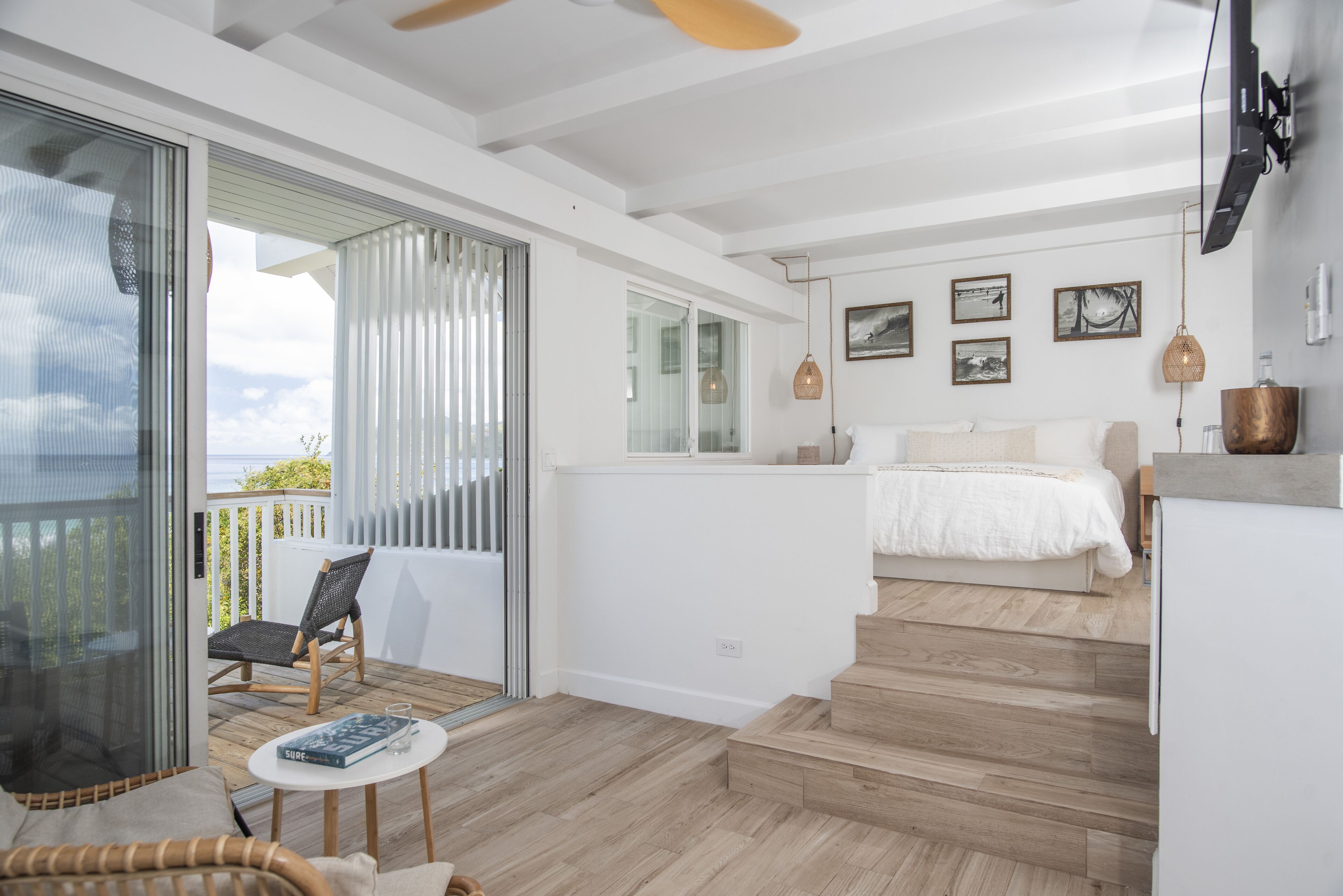 Un dormitorio moderno con una cama grande, un balcón con una silla y vistas al cielo.