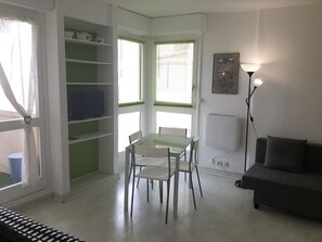 A compact living space with a dining area, a sofa, and a bookshelf.