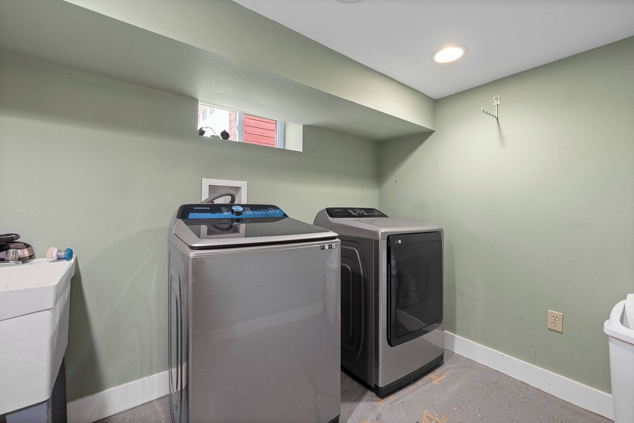 A laundry room with a washing machine, dryer, and a small window.