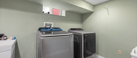 A laundry room with a washing machine, dryer, and a small window.