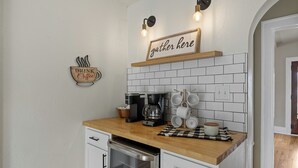 Una cocina con cafetera, tazas y un cartel que dice "DRINK Coffee".