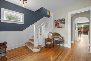 Staircase leads to an upper level, with a chair and table below.