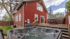Una casa roja con un jacuzzi en el patio trasero.