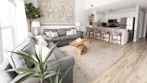 Ein modernes Wohnzimmer mit grauem Sofa, Couchtisch aus Holz und einem großen Gemälde an der Wand.