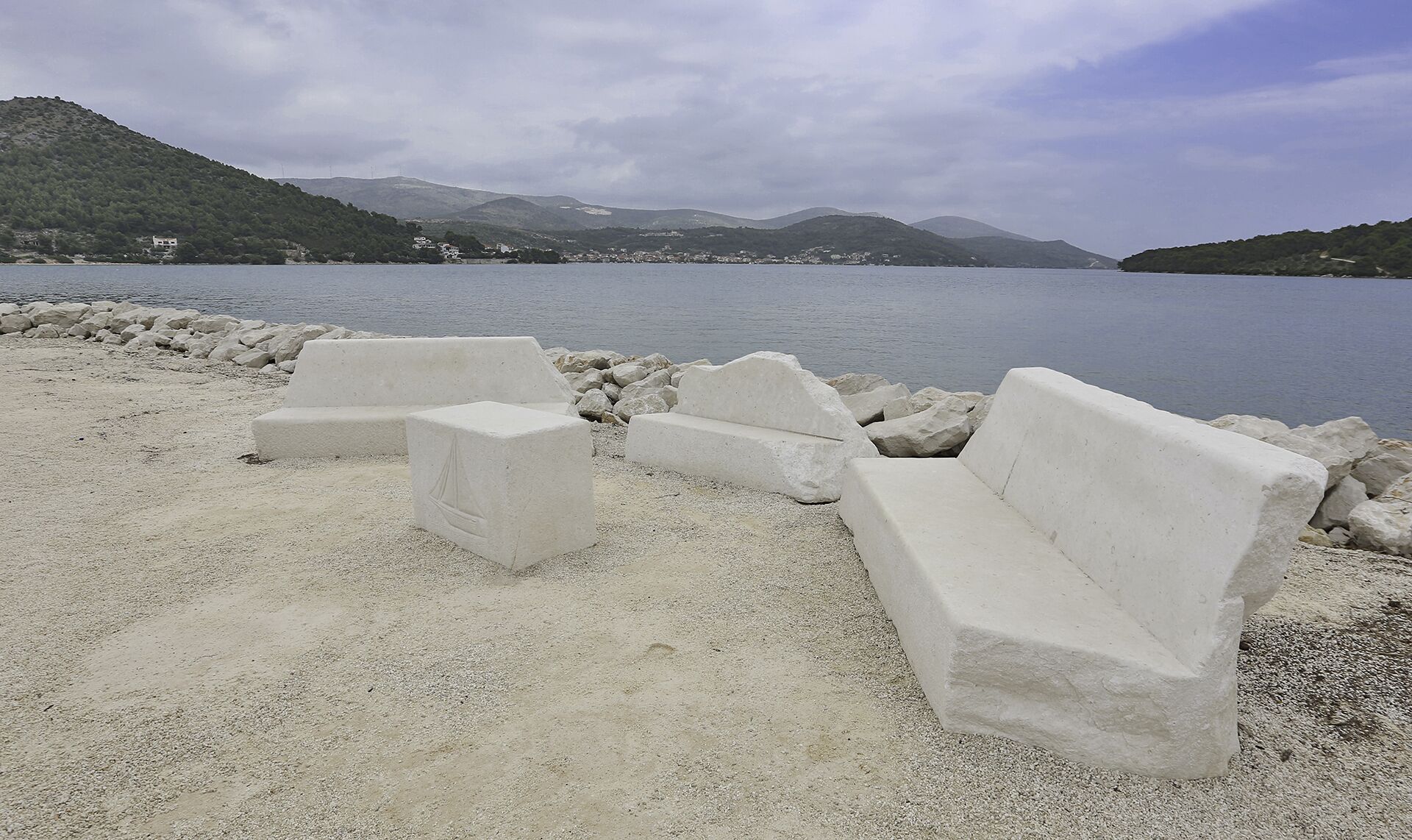 A beach with concrete seating and a rocky shoreline.