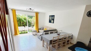 A spacious living area with a dining table, chairs, a sofa, and a kitchen counter. - Villa Jolymelody (Santa-Maria-Poggio)