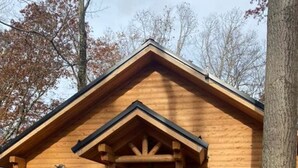 A wooden cabin with a black door, a small porch, and a window. - Malbec Cabin - 6 Guests - Hocking Hills - Hot Tub-Firepit-Wifi (Logan)