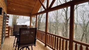 A wooden deck with a table and chairs, a ceiling fan, and a view of trees through large windows. - Malbec Cabin - 6 Guests - Hocking Hills - Hot Tub-Firepit-Wifi (Logan)