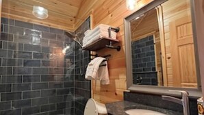 A wooden-paneled bathroom with a toilet, sink, and mirror. - Malbec Cabin - 6 Guests - Hocking Hills - Hot Tub-Firepit-Wifi (Logan)