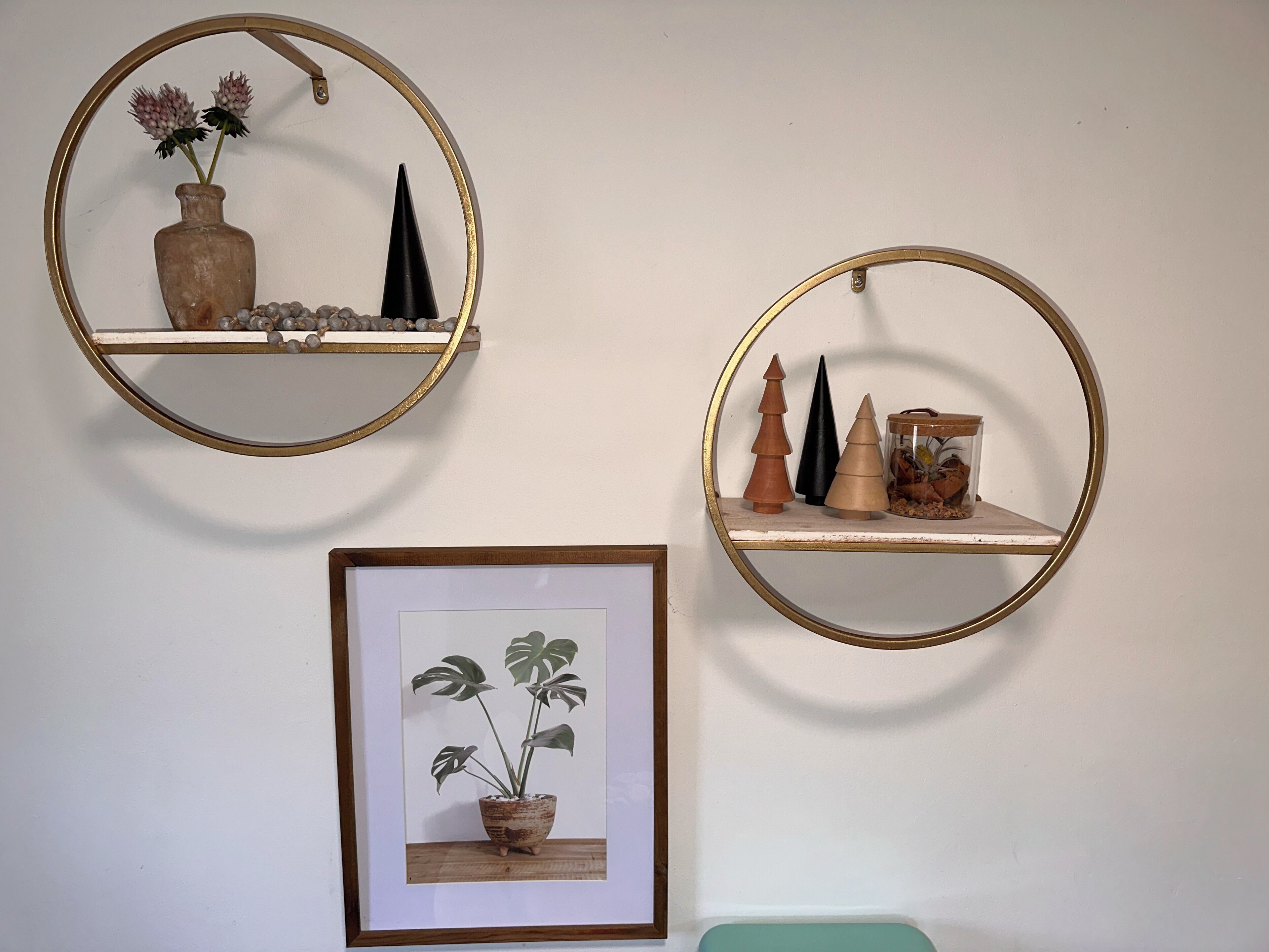 Tres repisas fijas a la pared con objetos decorativos, incluyendo un cuadro con una planta.