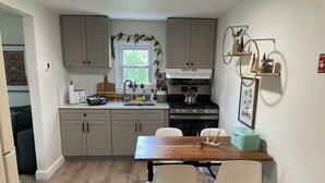 A modern kitchen with light-colored cabinets, a wooden dining table, and white chairs. - Create Memories at our Modern Waterfront 1 BR Apartment: Hike, Sip Wine, Relax!  (Wallkill)