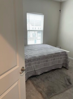Cozy bedroom with a bed, window, and door.