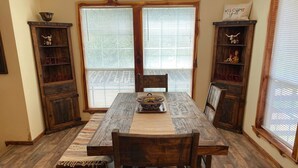 A dining area with a wooden table, chairs, and a central rug. There are two wooden cabinets with decorative items on the sides. - Beautiful Longhorn Lodge at Lake Texoma! (Gordonville)