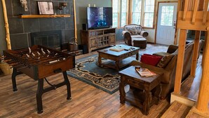 A cozy living room with a foosball table, a fireplace, a television, and a comfortable seating area. - Beautiful Longhorn Lodge at Lake Texoma! (Gordonville)