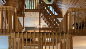 A multi-level wooden interior with a sofa and a dining area. - Beautiful Longhorn Lodge at Lake Texoma! (Gordonville)