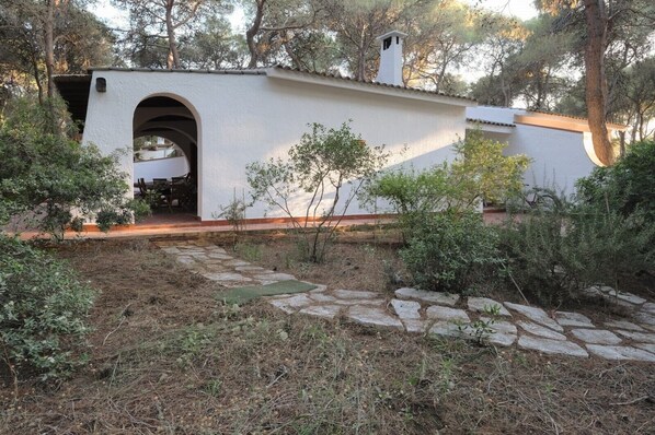 A rustic building with an arched entrance, surrounded by a stone pathway and greenery.