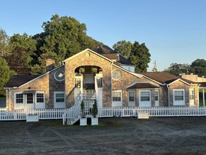 A stone building with a white picket fence, a central staircase, and a small porch area.