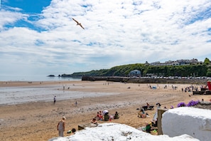 A beach with people, a seagull, and buildings in the background.