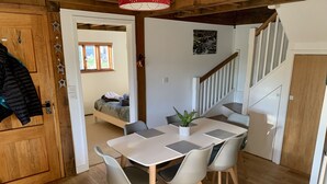 Ein Essbereich mit Tisch, Stühlen und einem Blumentopf. Eine Treppe führt in einen anderen Raum.