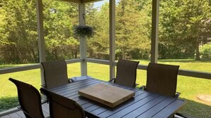 A covered patio with a table and chairs, a hanging planter, and a view of a well-maintained lawn and trees. - Perfect Getaway - Cozy Cottage in The Galena Territory (Galena)