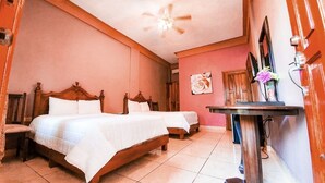 A room with two wooden beds, a small table, and a ceiling fan.