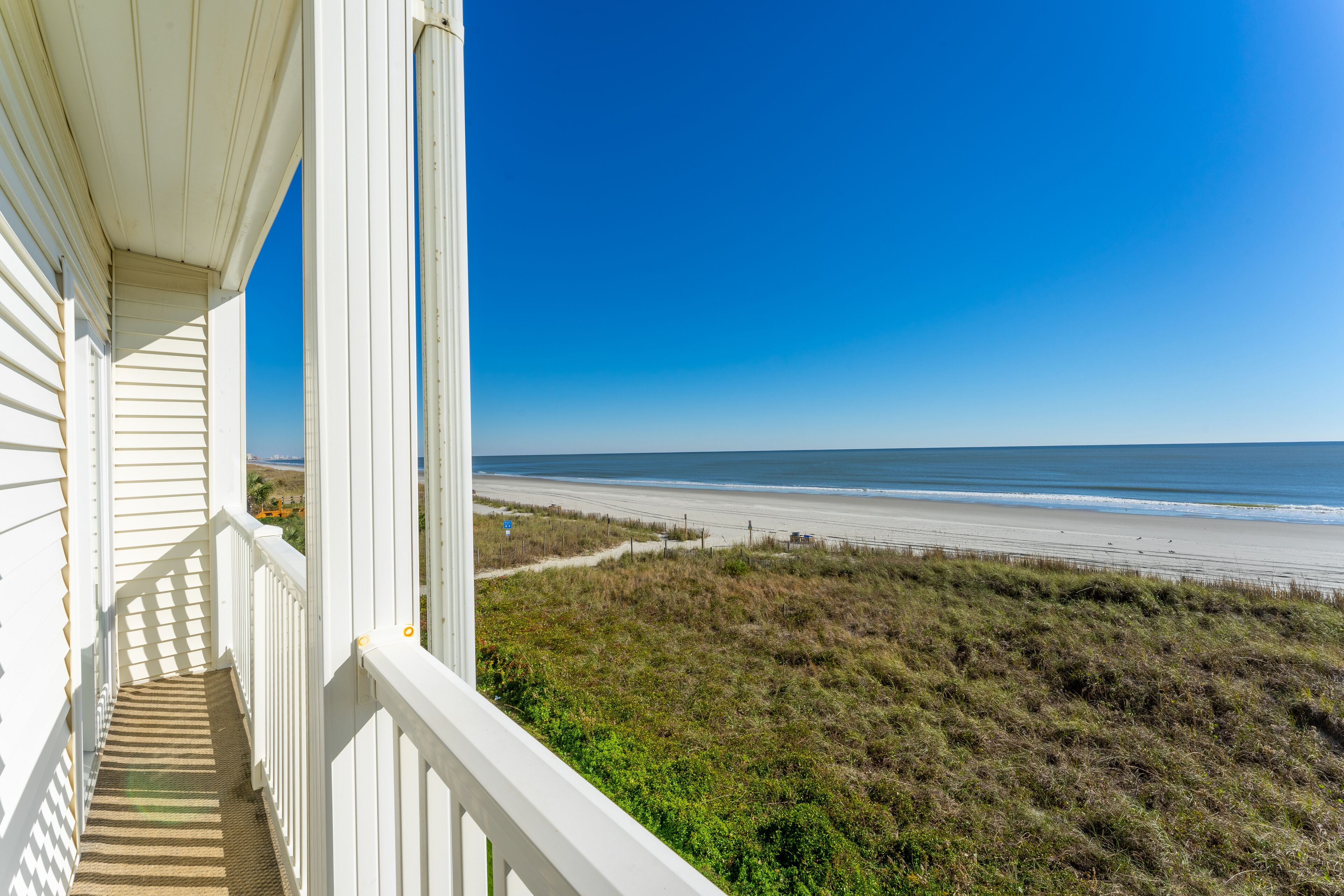 Een balkon met uitzicht op het strand en de zee.